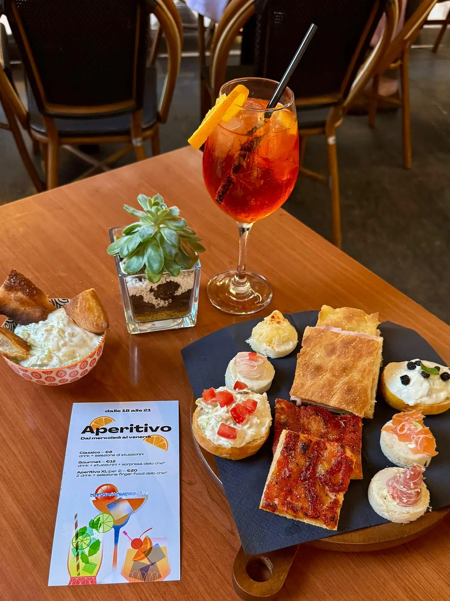 Un tavolo dell'aperitivo: spritz, pizzette, tartine e il menù