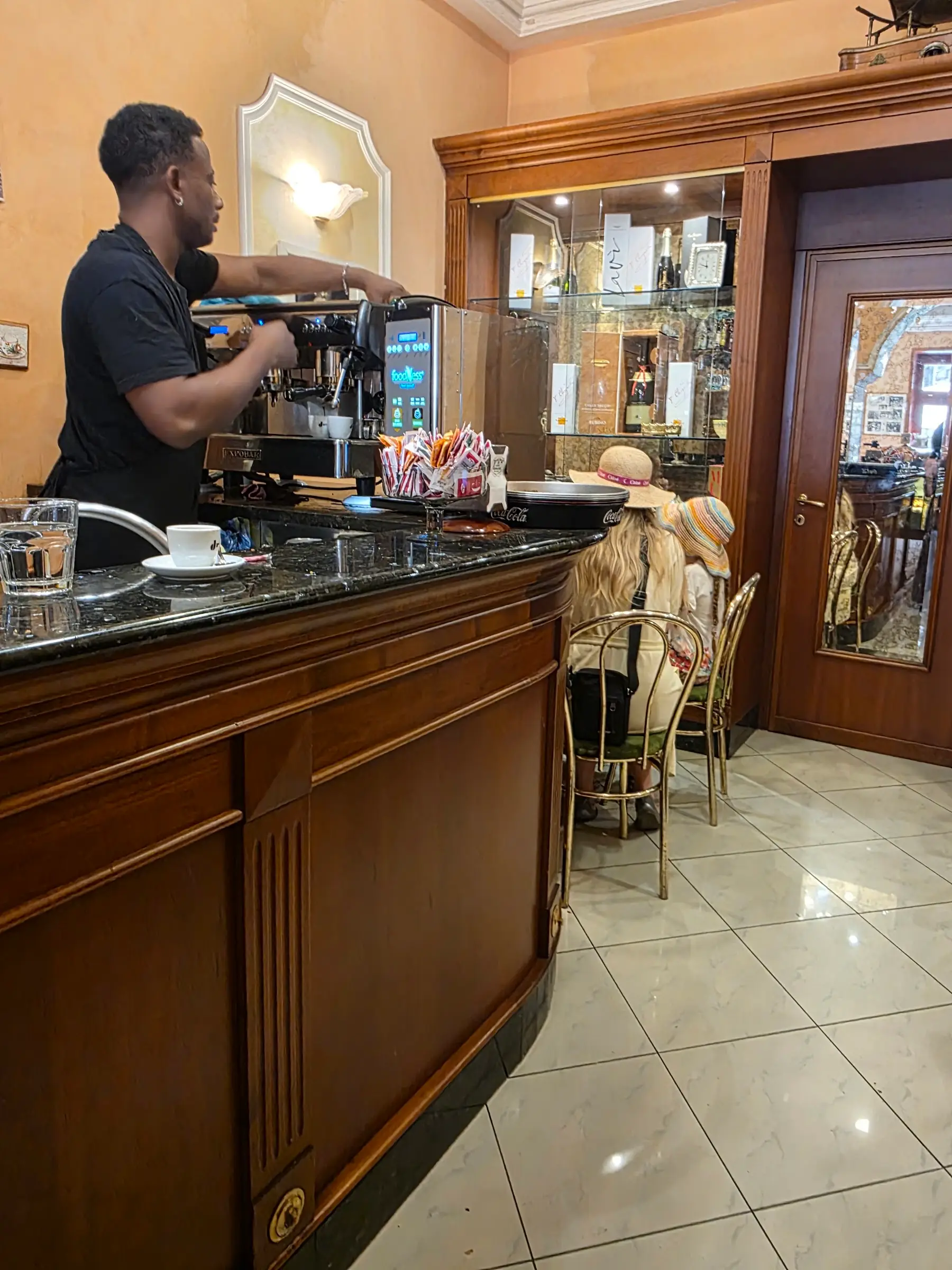Il bancone in legno scuro di Sanzini, con il barista alla macchina del caffè