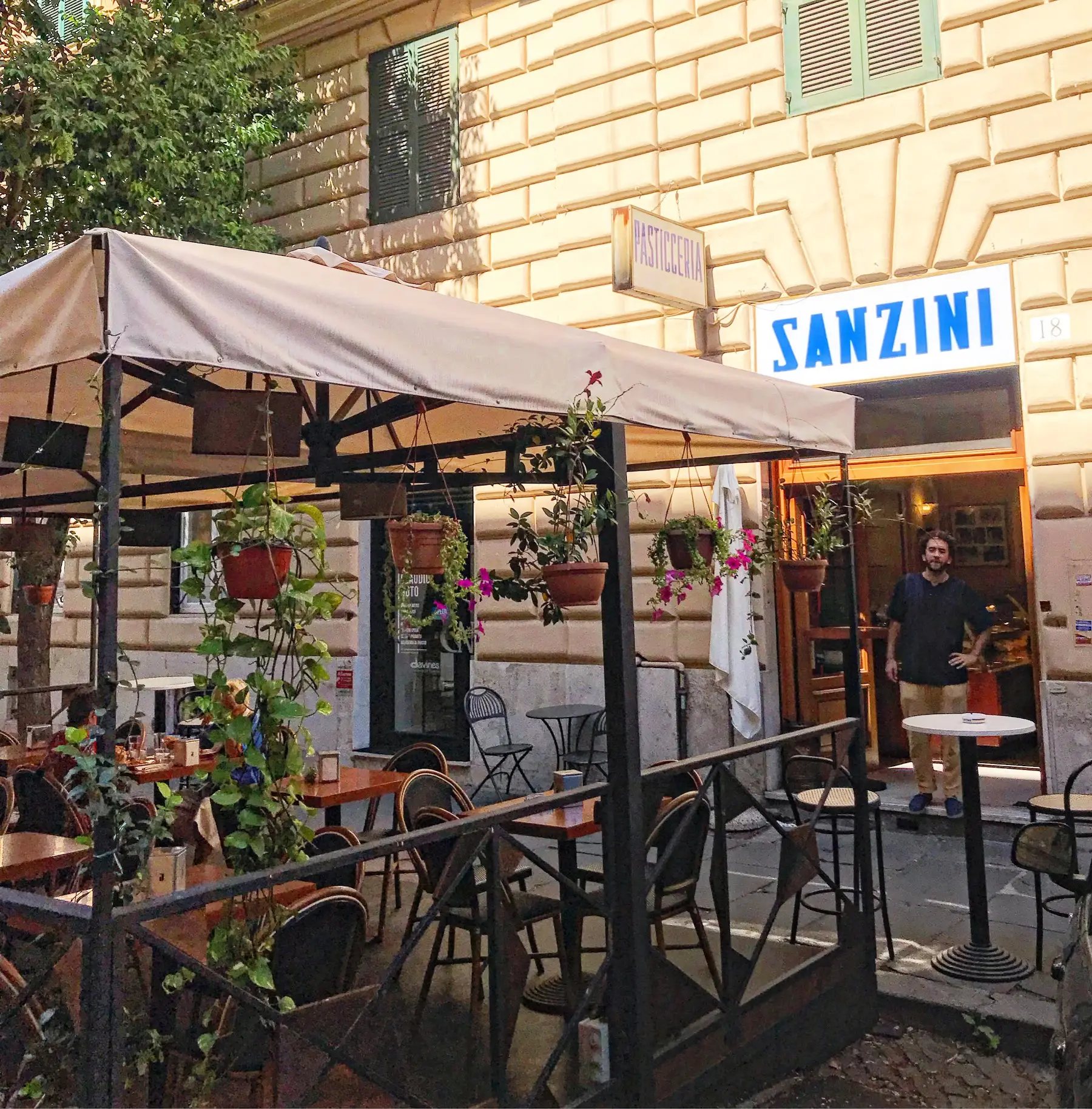 Il dehors di Sanzini con i tavolini sotto la tenda e i vasi di gerani