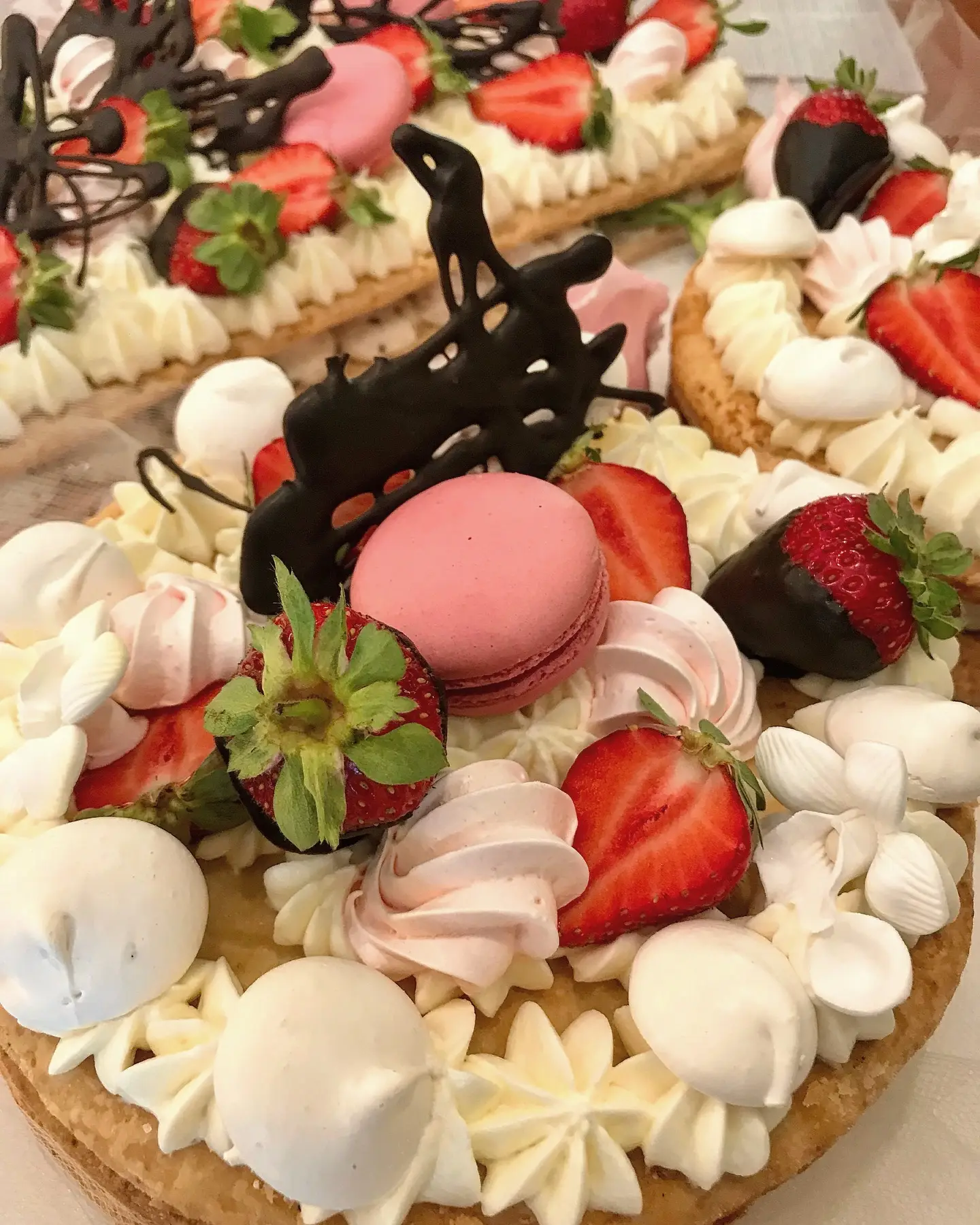 Una torta con crema, fragole, macaron e meringhe